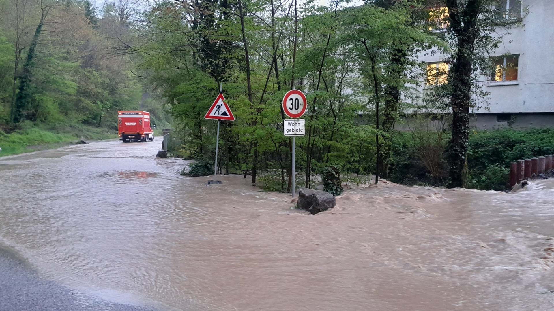 Überschwemmte Straße in Gundelsheim mit einem Einsatzfahrzeug der Feuerwehr